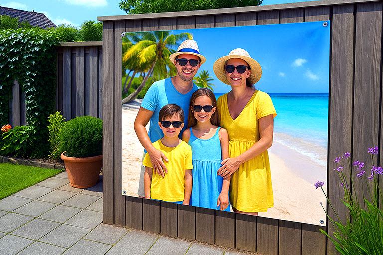 Tuinposter groot in een tuin. Op de poster staat een gezin van 4 personen op een strand